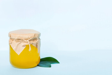 Honey in jar with leaves and honey dipper on colored background top view with copy text