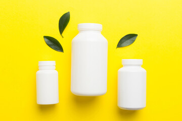 supplement pills with medicine bottle health care and medical top view. Vitamin tablets. Top view mockup bottle for pills and vitamins with green leaves, natural organic bio supplement, copy space