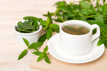 Cup of mint tea on table background. Green tea with fresh mint top view with copy space