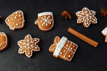 Christmas cookies snowflake tree mitten gift shaped gingerbread with icing on dark background with cinnamon sticks