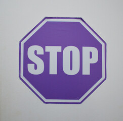 purple stop sign symbol displayed on a white wall, offering a modern twist on the traditional red traffic sign. This minimalist and bold concept image can symbolize awareness, caution.