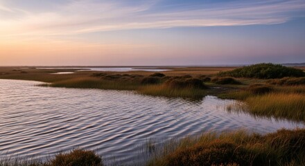 Serene coastal marsh landscape at dusk, showcasing water, reeds, and a vibrant sunset sky