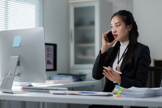 Asian businesswoman having important business call in office