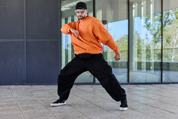 A young European guy in stylish clothes is practicing dance moves