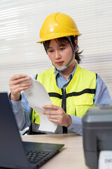 Asian female engineer uses a laptop or notebook to print barcode stickers on a barcode printer.