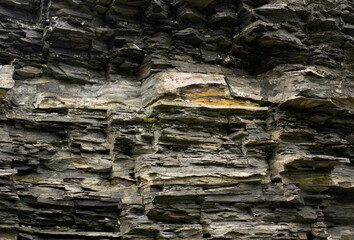 Black yellow rock texture. Mountain surface. Close-up. Gray stone background with copy space for design. Wide banner. Panoramic.