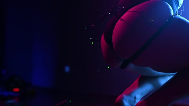 A young woman dances with garlands under neon lights.