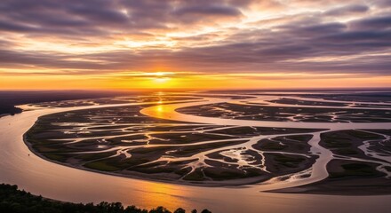 Aerial view of a winding river delta under a vibrant, cloud-filled sunset, reflecting golden light