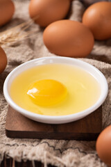 Broken raw egg with yolk on wooden table.