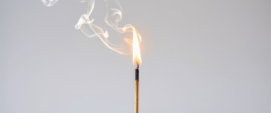 Single wooden matchstick with flame and smoke on gray background, isolated object, fire ignition concept.
