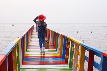 Woman in Red Hat Walking on Rainbow Wooden Bridge