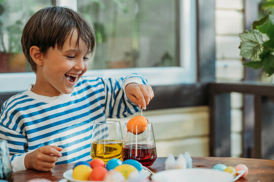 Happy boy removing easter egg from colored glass at front porch