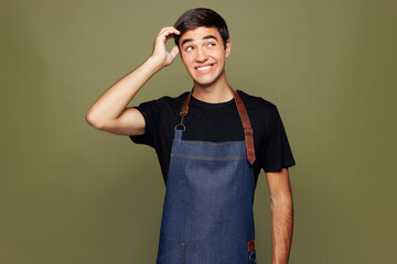 Young minded sad man barista bartender barman employee he wear jeans apron black t-shirt work in...