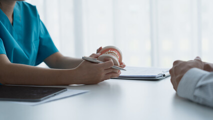 Dentist Examining Healthy Tooth Model While Consulting Patient