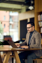 Fototapeta premium Professional Man Working On Laptop In Modern Café, Focused On Work And Quiet Ambience