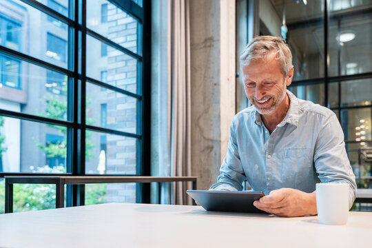 Smiling businessman using tablet at modern office desk