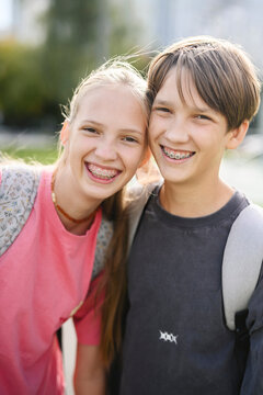 Smiling siblings with backpacks outdoors after school