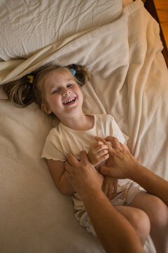 Girl laughing while being tickled by parent indoors on bed