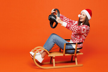 Full body side view merry young woman wear red Christmas sweater Santa hat posing hold steering...