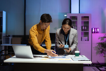 Business team analyzing data with laptops and graphs in office.