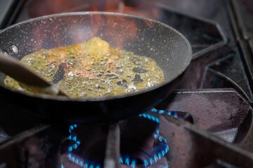 A close-up of sugar caramelizing in hot pan on gas stove, golden bubbles forming under heat, food preparation concept for dessert cooking.