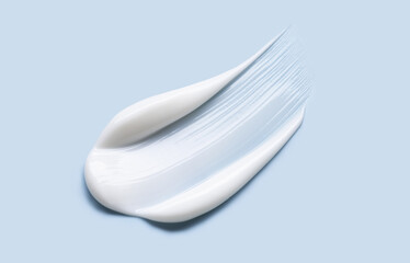 Close-up of cosmetic cream smear, smooth and shiny texture, blue background