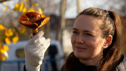 A poisonous mushroom. A woman holds a golden scaly cap and examines it closely in autumn.