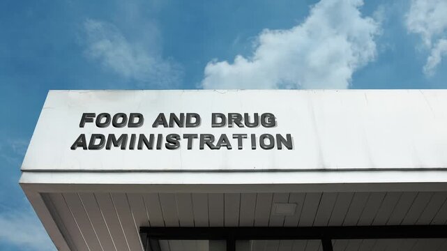 Food and Drug Administration word sign prominently displayed on the official government building facade beneath a clear blue sky, signifying the national agency regulating food, drugs, public health