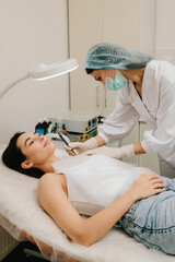 Dermatologist performs precise radio wave mole removal using radiofrequency surgery. Close-up of radio wave dermatologic mole excision. Radiofrequency mole removal under clinical conditions.