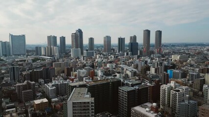 Drone pulls back over Musashi Kosugi showing skyline of Japan trade integration