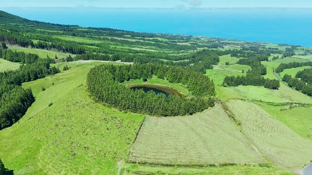 Scenic round Pau Pique lake in caldera surrounded by trees on Sao Miguel, Azores. Aerial view