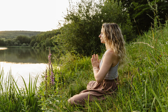 Wiman meditating in nature by a lake on a calm summer day