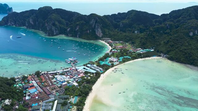 Phi Phi Don Island, a popular tourist destination. A village and pier between two bays, a drone flight over the islands in Thailand.