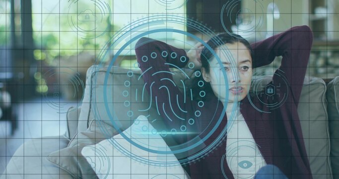 Reclining woman wearing maroon cardigan at home on sofa by windows with holographic interface