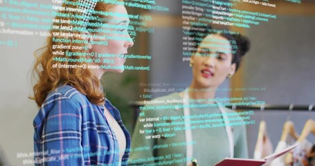 Two colleagues discussing code snippets in office with binder, plant, clothing rack