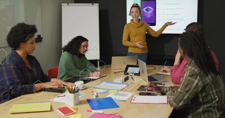 Presenter explaining design concepts in conference room, with printed charts laptops color swatches