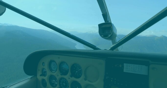 Fototapeta Cockpit panel showing analog gauges in flight framing mountain lake, with radio stack and camera
