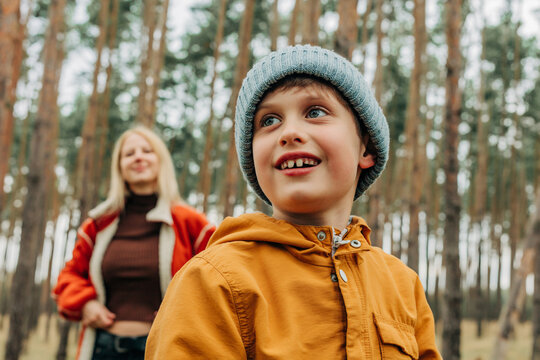 Smiling child with woman in autumn pine forest enjoying relaxation