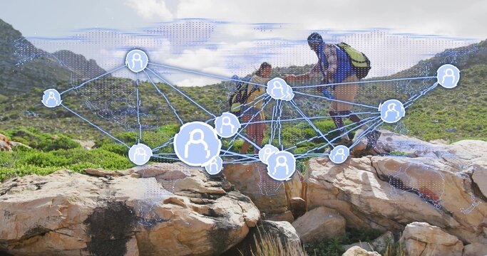 Navigating two hikers crossing rocky outcrop on mountain ridge trail, with digital network overlay - Powered by Adobe