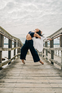 Young woman dancing ballet outdoors on wooden pier