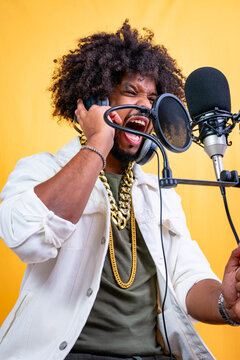 Black man vigorously recording rap vocals in studio