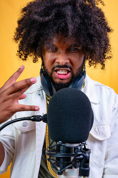 A man raps into a microphone, expressing intense emotion.