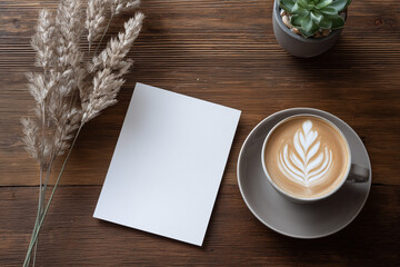 A top view of a blank card, coffee, plant, and dried flowers on a wooden surface
