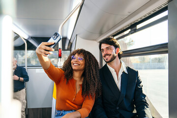 Happy couple traveling on city bus, capturing a joyful moment with a smartphone. Modern technology in public transport