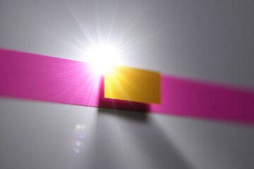 レーザー光のスポットが付いたピンクと黄色の紙のストリップ。