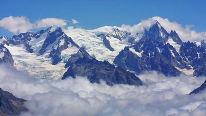 Obraz premium Snow Covered Peaks Above the Clouds