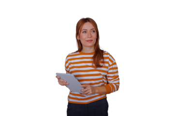 Redhead woman holding a tablet, smiling and looking away, standing in comfortable clothes, showing digital concept