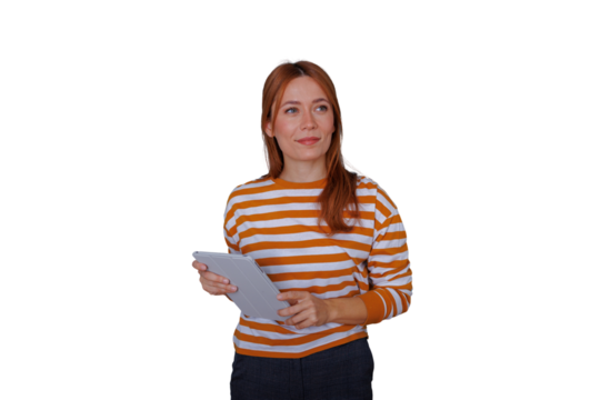 Redhead woman holding a tablet, smiling and looking away, standing in comfortable clothes, showing digital concept