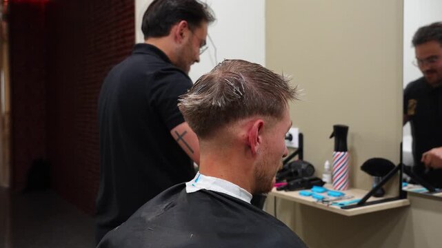 Hairdresser dusts customer&rsquo;s neck after haircut while he smiles happily