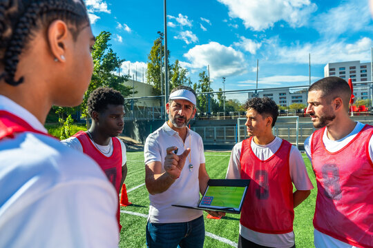 Coach discussing soccer strategy with diverse team players